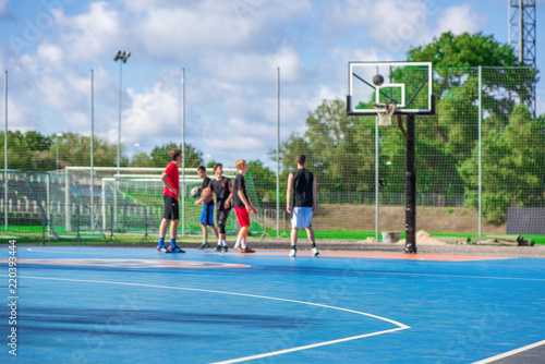Abstract, blurry background of boys playing basketball in outdoor basketball court in park  