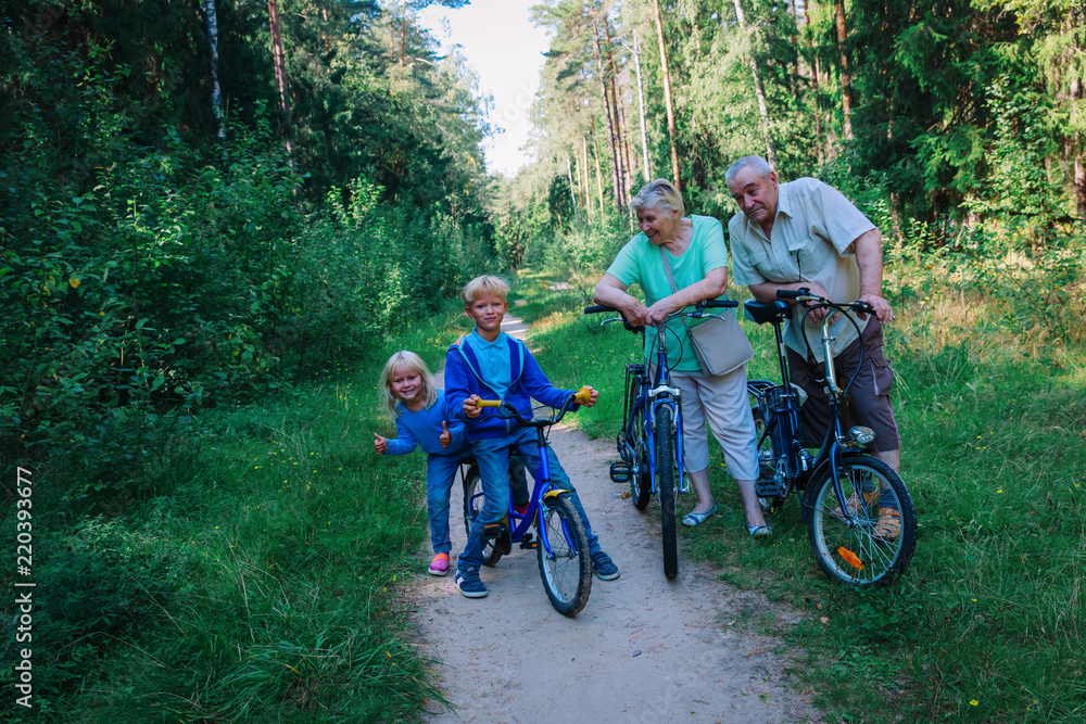 active senior couple with kids riding bikes in nature active senior couple with kids riding bikes in nature