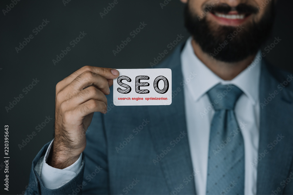 cropped view of smiling developer and showing business card with SEO sign cropped view of smiling developer and showing business card with SEO sign