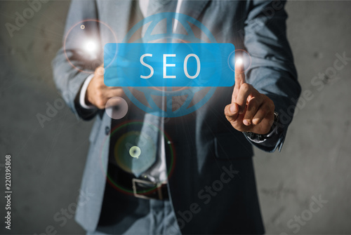 cropped view of developer in formal wear pointing at SEO sign