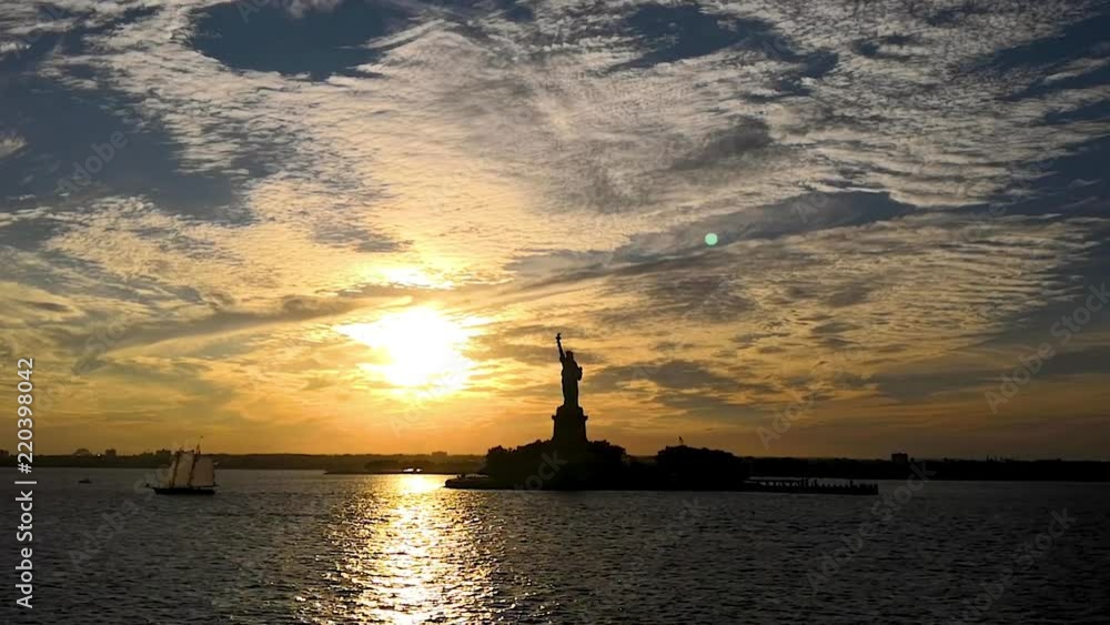 A dramatic sunset next to the Statue of Liberty in the Upper Bay in New York City, Manhattan in the summer. A dramatic sunset next to the Statue of Liberty in the Upper Bay in New York City, Manhattan in the summer.