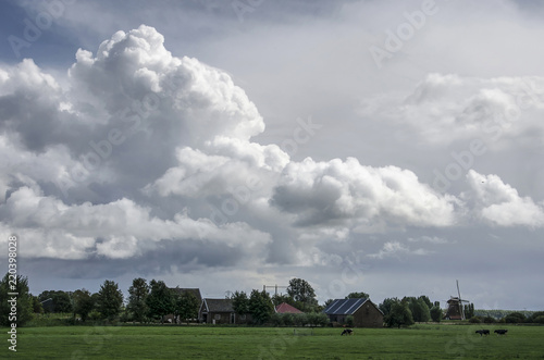 Dramatic cloudscape over a polder landscape with grassland, a farm and a windmill near Nigtevecht, The Netherlands photo