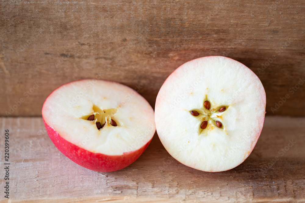 Cut apple on a wooden plank, showing the seeds in a delicate five pointed star motive