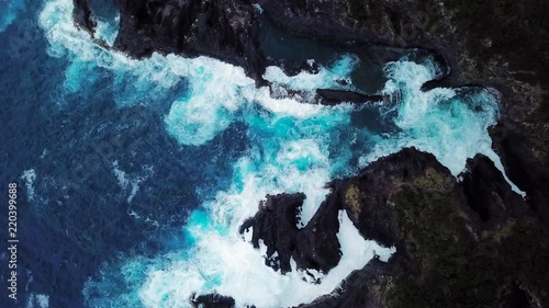 Beautiful azure blue ocean waves breaking onto the rocks. The Lava Coast at Fajã do Ouvidor in Sao Jorge Island, Azores. Portugal. Aerial Topdown Shot photo