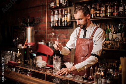 Bartender stirring an ice cubes in the cocktail