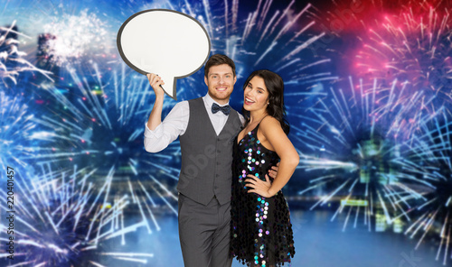 holidays, celebration and communication concept - happy couple hugging at party and holding blank text bubble banner over firework background