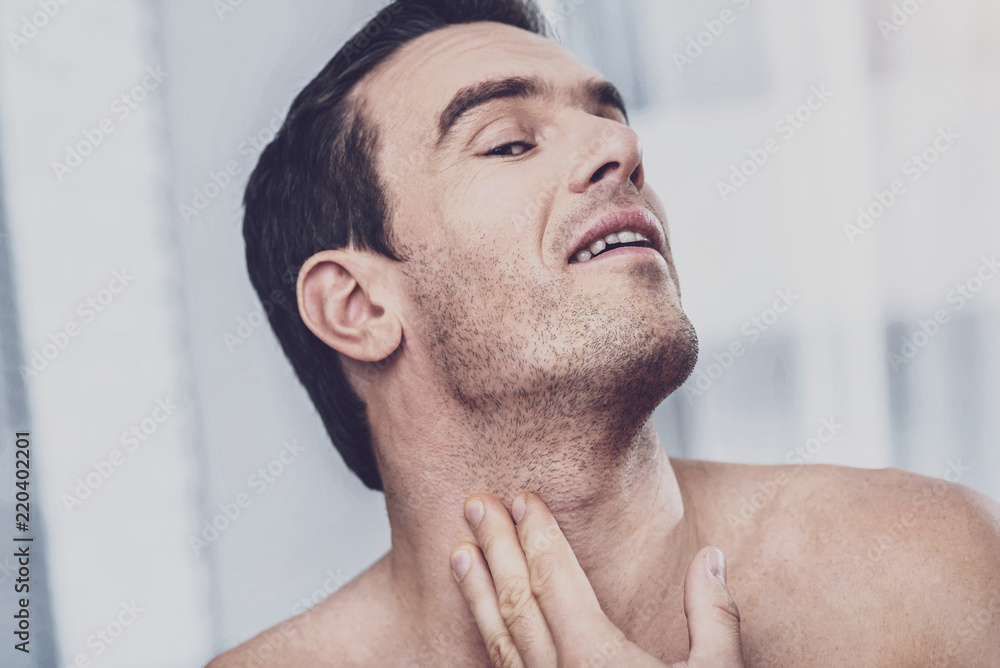 Obraz premium Skin care. Close up of charismatic unshaven man standing in front of the mirror and looking at the bristle of his face