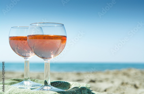 Beach party with sea view, romantic celebration on sunny sandy beach, two glasses with rose wine