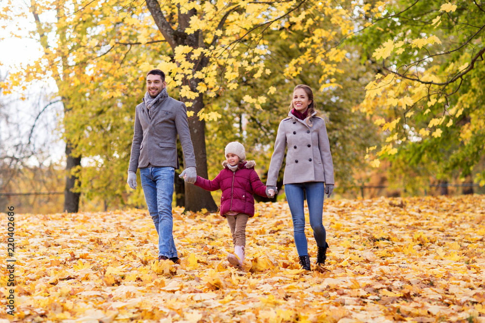 Obraz premium family, season and people concept - happy mother, father and little daughter walking at autumn park