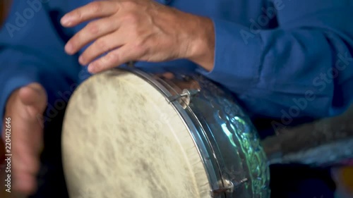 Closeup of playing fast drumming rhythm on metal Turkish daholla with arabic background. photo