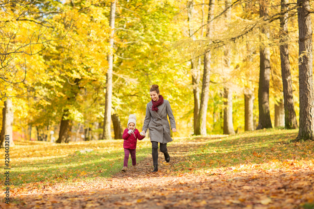 family, season and people concept - happy mother and little daughter walking along autumn park family, season and people concept - happy mother and little daughter walking along autumn park