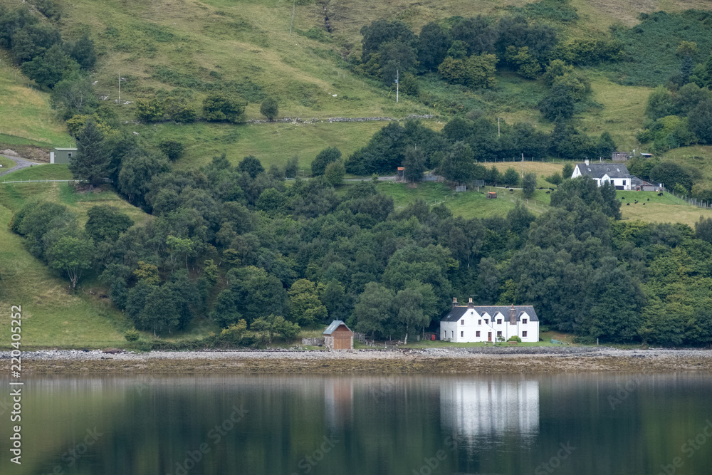 Loch Broom, Inverness, Scotland. White painted house on the shore of the loch, reflected in the water. 