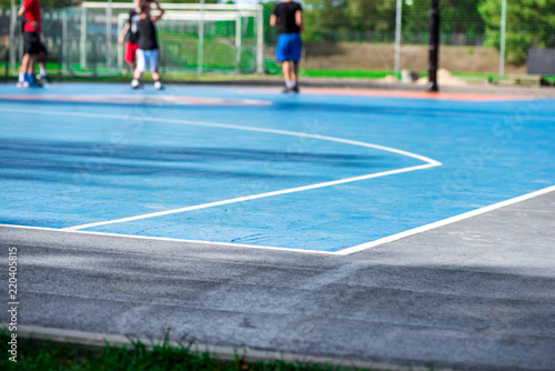 Abstract, blurry background of boys playing basketball in outdoor basketball court in park 