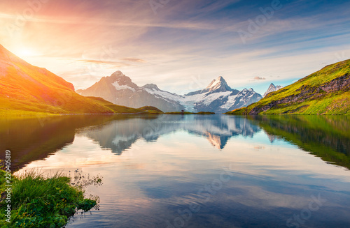 Colorful summer sunrise on Bachalpsee lake with Schreckhorn and Wetterhorn peaks on background.
