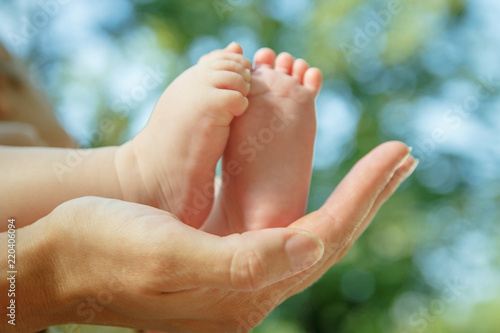 Mother holding bare baby feet outdoor