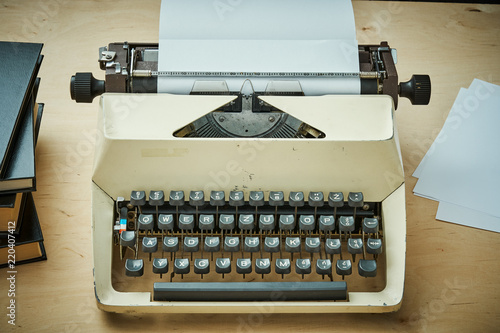 bright old typewriter with gray keys and books on a wooden table