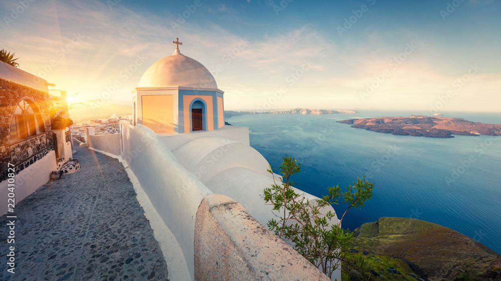 Fototapeta premium Sunny morning panorama of Santorini island. Picturesque spring sunrise on the famous Greek resort Thira, Greece, Europe. Traveling concept background. Artistic style post processed photo.