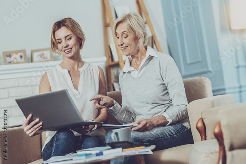 New ideas. Positive aged woman pointing at the laptop while discussing work together