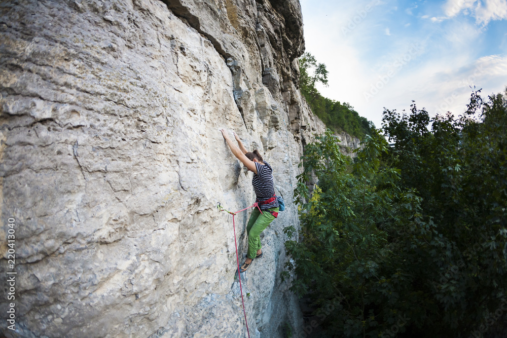 Sports girl climbs on the rock.