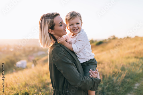 Quadro em tela happy young mother carrying adorable smiling little son at sunset
