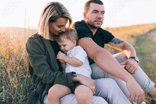 beautiful happy family with one child sitting together outdoors