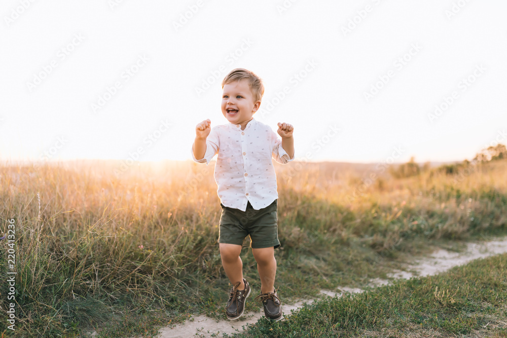 adorable happy little boy walking on rural path at sunset adorable happy little boy walking on rural path at sunset