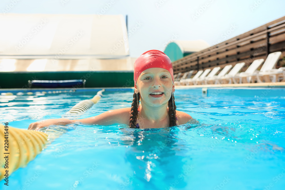 The portrait of happy smiling beautiful teen girl at the swimming pool. Little child at blue wate. Pool, leisure, swimming, summer, recreation, healthy lifstyle concept