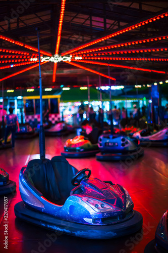 Front view from bumper cars in an amusement park. In this photo: Stopped bumper cars, neon lights, fun, no people and night photo.