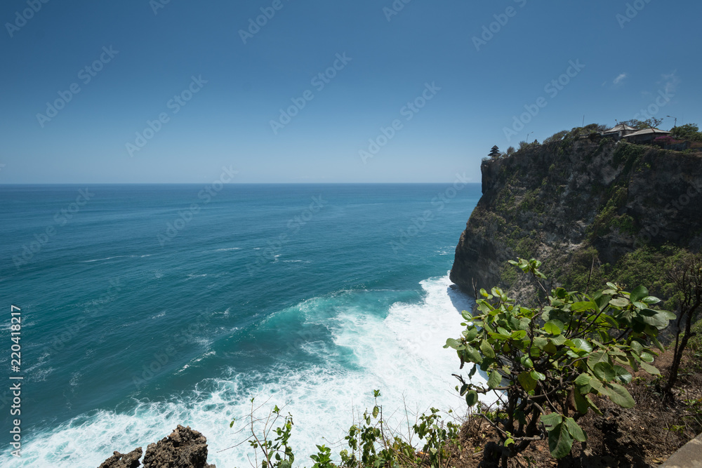 cliff steep with waves and surf in uluwatu temple blue water in bali indonesia