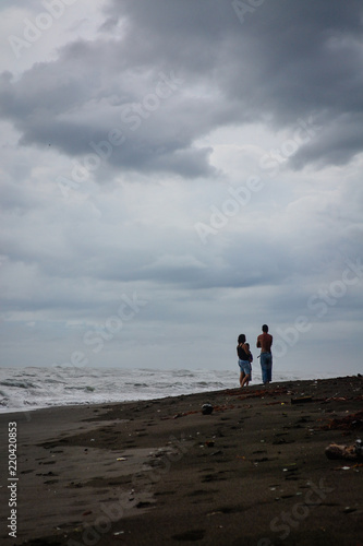 couple walking on the beach with dark sand