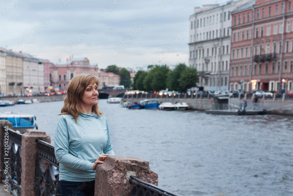 A happy retired woman traveling around Europe. White nights in Saint-Petersburg, Russia.