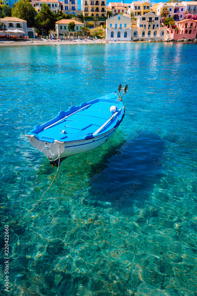 Blue fishing boat in the emerald azure rippled sea water bay in Assos village, Kefalonia island, Greece Blue fishing boat in the emerald azure rippled sea water bay in Assos village, Kefalonia island, Greece