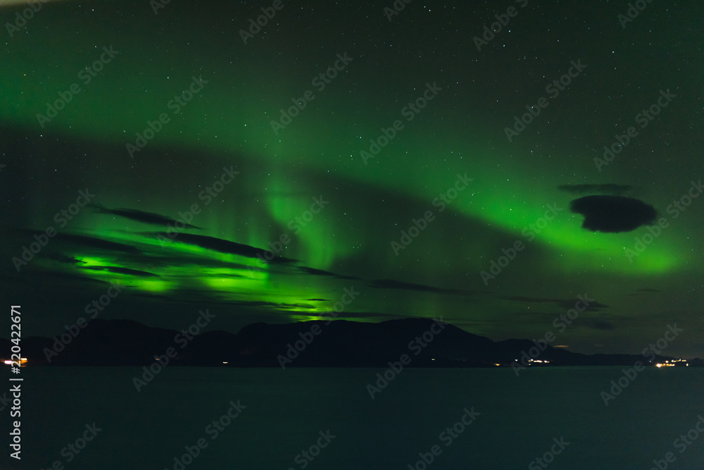 norwegian aurora borealis with mountains and water, view from hurtigruten ship boat, norway, europe, green northern lights