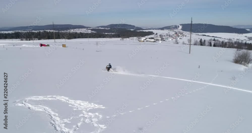Aerial view: A snow motorcycle. Driving in the snow against the background of the amazing mountains Aerial view: A snow motorcycle. Driving in the snow against the background of the amazing mountains