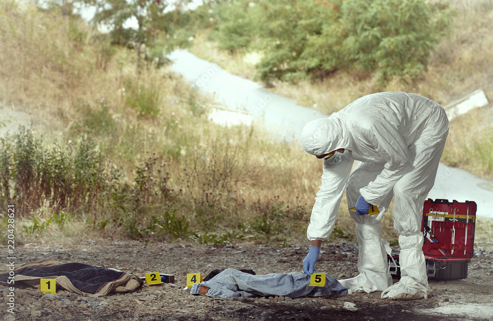 Criminologist technician in DNA free protective suit collecting evidences of probable criminal act Criminologist technician in DNA free protective suit collecting evidences of probable criminal act