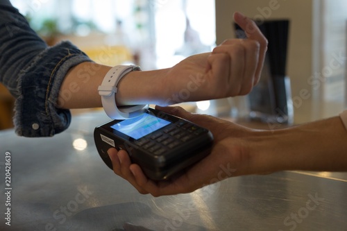Woman paying with NFC technology on smartwatch in cafe
