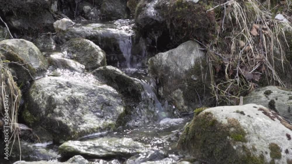 Water coming down from a small waterfall with rocks Water coming down from a small waterfall with rocks