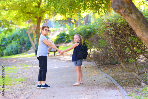Grandma and pupil kid holding hands going to school.Little girl with school bag or satchel walking to school with grandmother. Old Parent and daughter, grandmother and granddaughter, back to school.