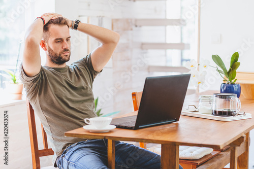 Young man having stressful time working on laptop