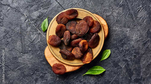 Brown sun dried apricots on black table. Top view of dry fruits with copy space. photo