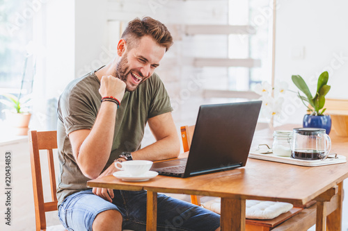 Young successful man working on laptop at home