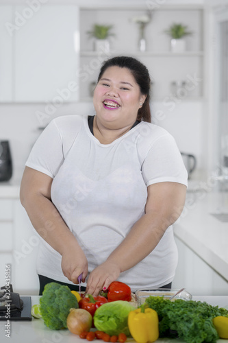 Asian fat woman cutting paprika in the kitchen