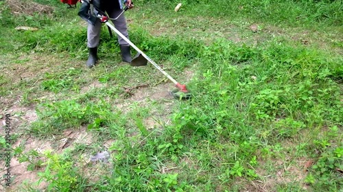 Woman cutting grass in garden with trimmer.