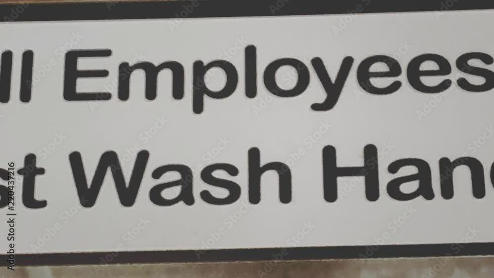 A pan shot of a restroom sign requiring employees to was their hands before returning to work. A pan shot of a restroom sign requiring employees to was their hands before returning to work.