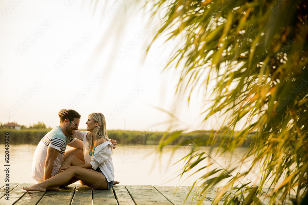 Romantic couple sitting on the wooden pier on the lake