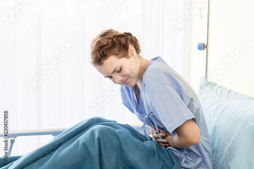 Beautiful young woman patient with period pain on hospital bed room.Copy space.