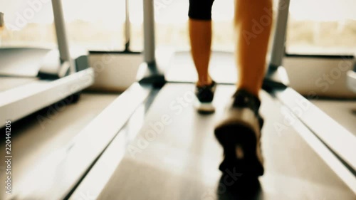 Close up blurry of sport woman legs running on treadmill in fitness gym sport center with window and sun light background. Exercise workout of diet and fat burning for healthy and wellness lifestyle.