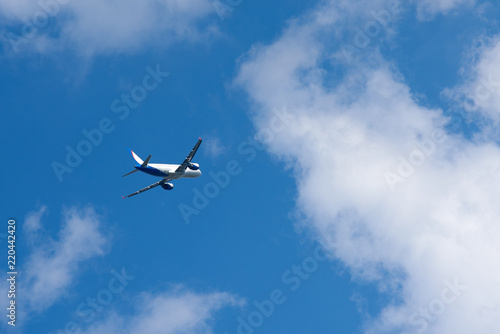 Passenger airplane gain altitude against blue sky and white clouds.