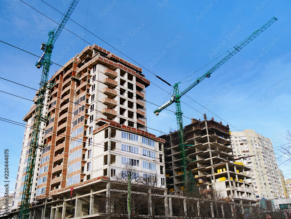 Construction site background. Commerxial construction project. Two cranes near building under construction