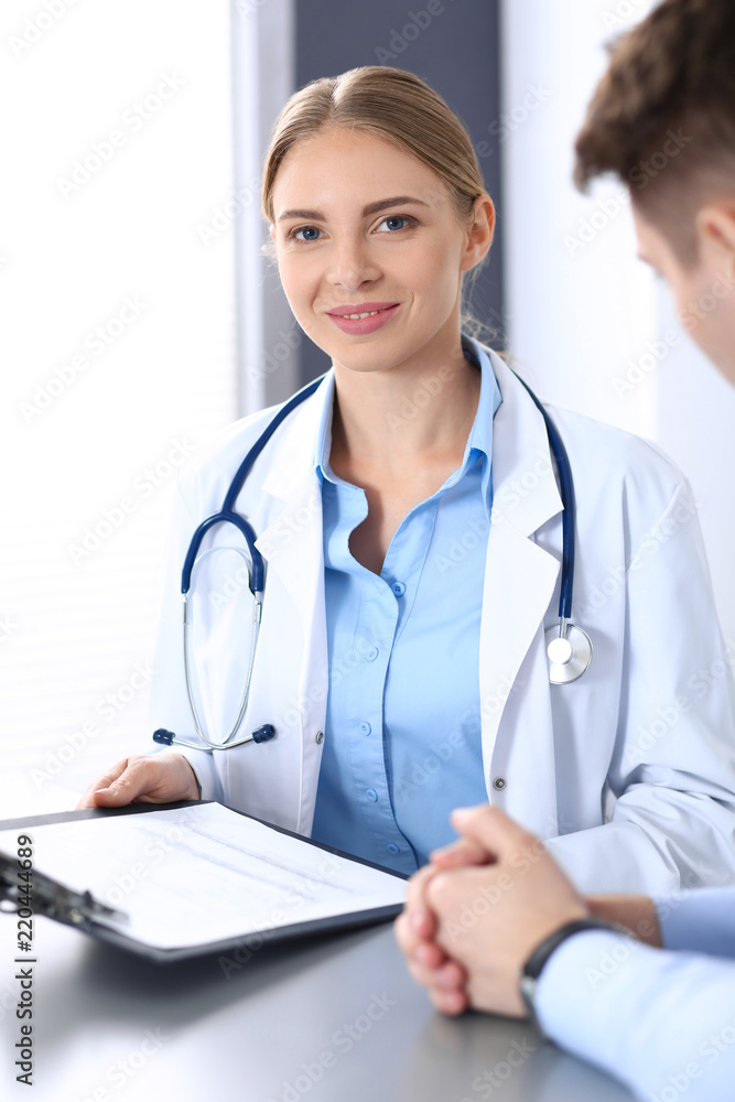 Doctor and patient in hospital. Beautiful blonde physician consulting business man about his health. Medicine concept Doctor and patient in hospital. Beautiful blonde physician consulting business man about his health. Medicine concept